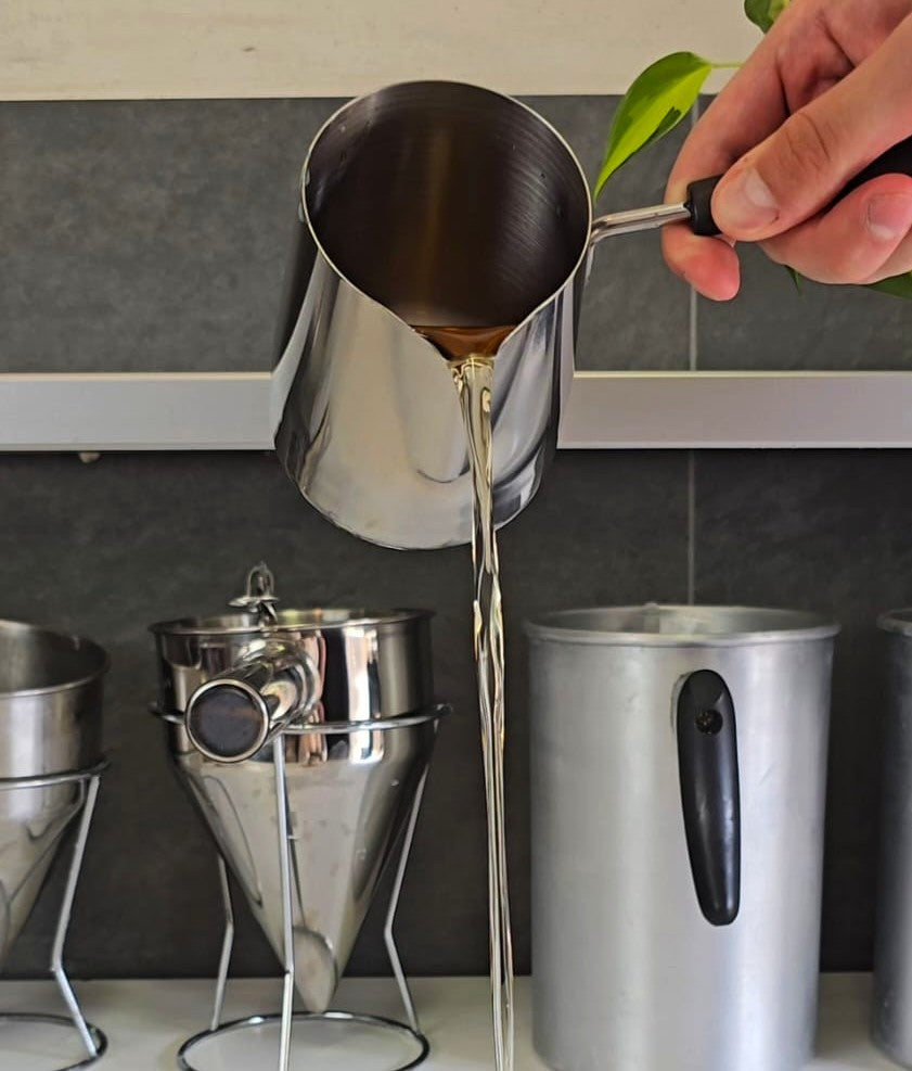 La cera fusa che cola dal bricco durante la preparazione delle candele EdÒra